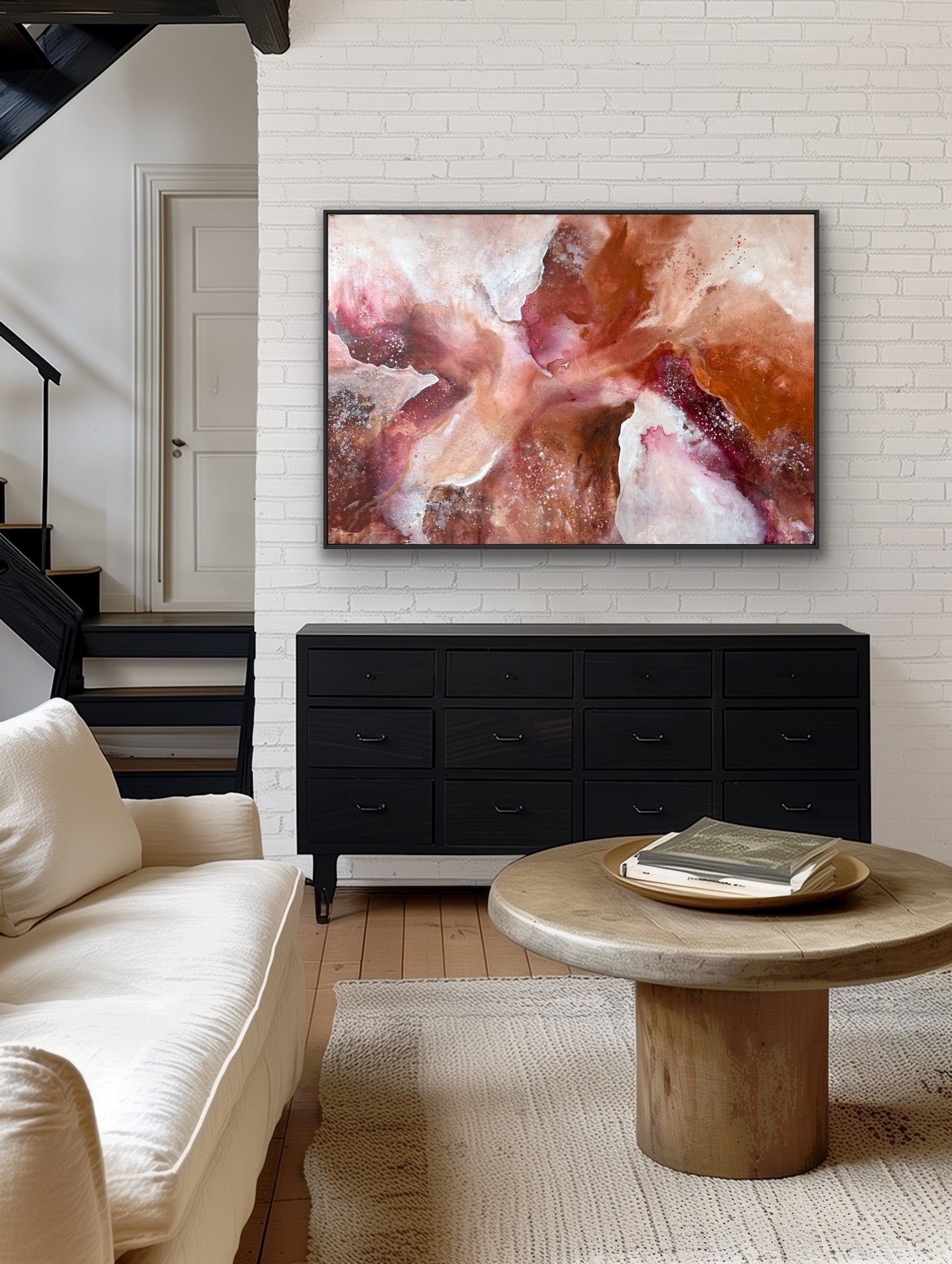 Living room with a black dresser, beige sofa, and abstract painting on a white brick wall.